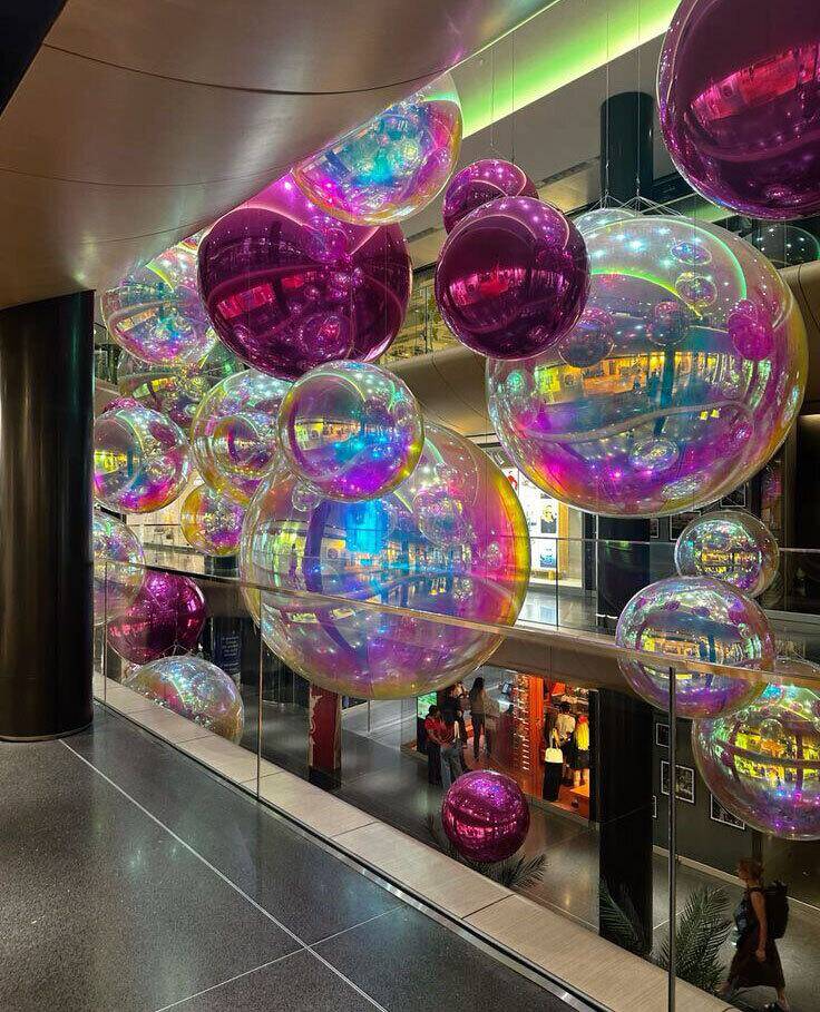 Ballons miroirs irisés suspendus dans un espace contemporain