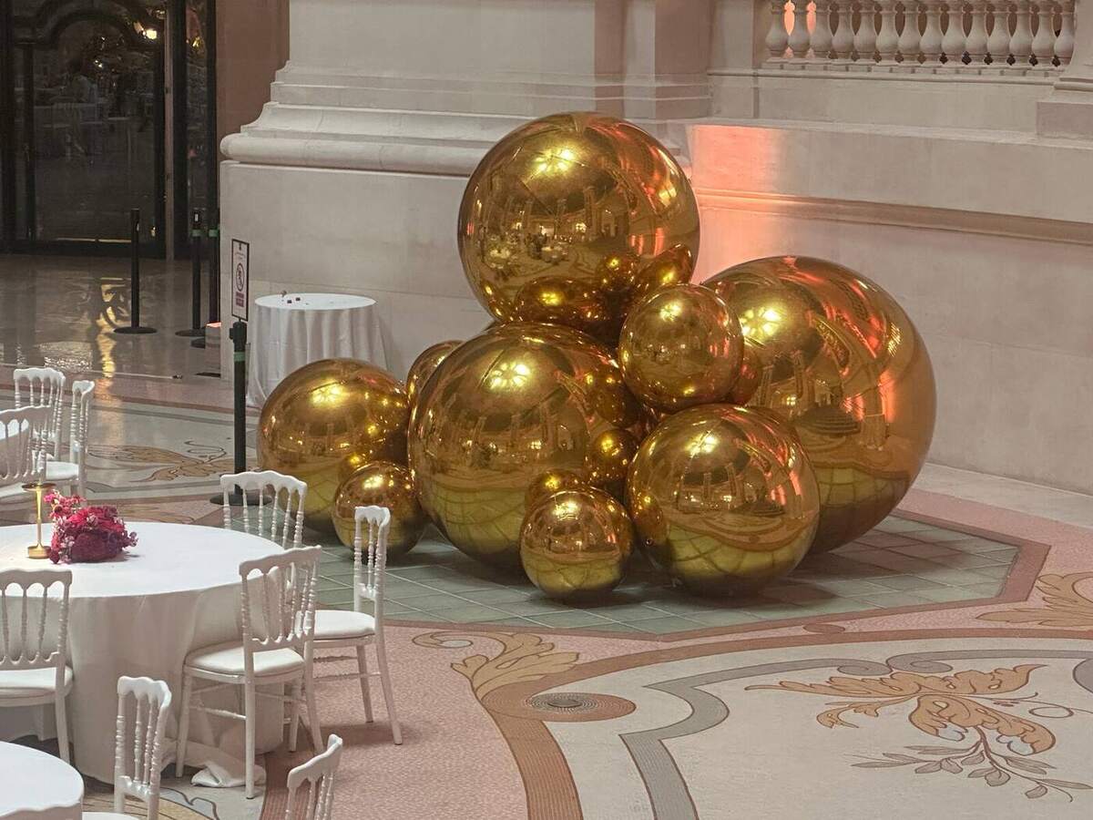 Groupe de ballons miroirs dorés installé dans une salle prestigieuse
