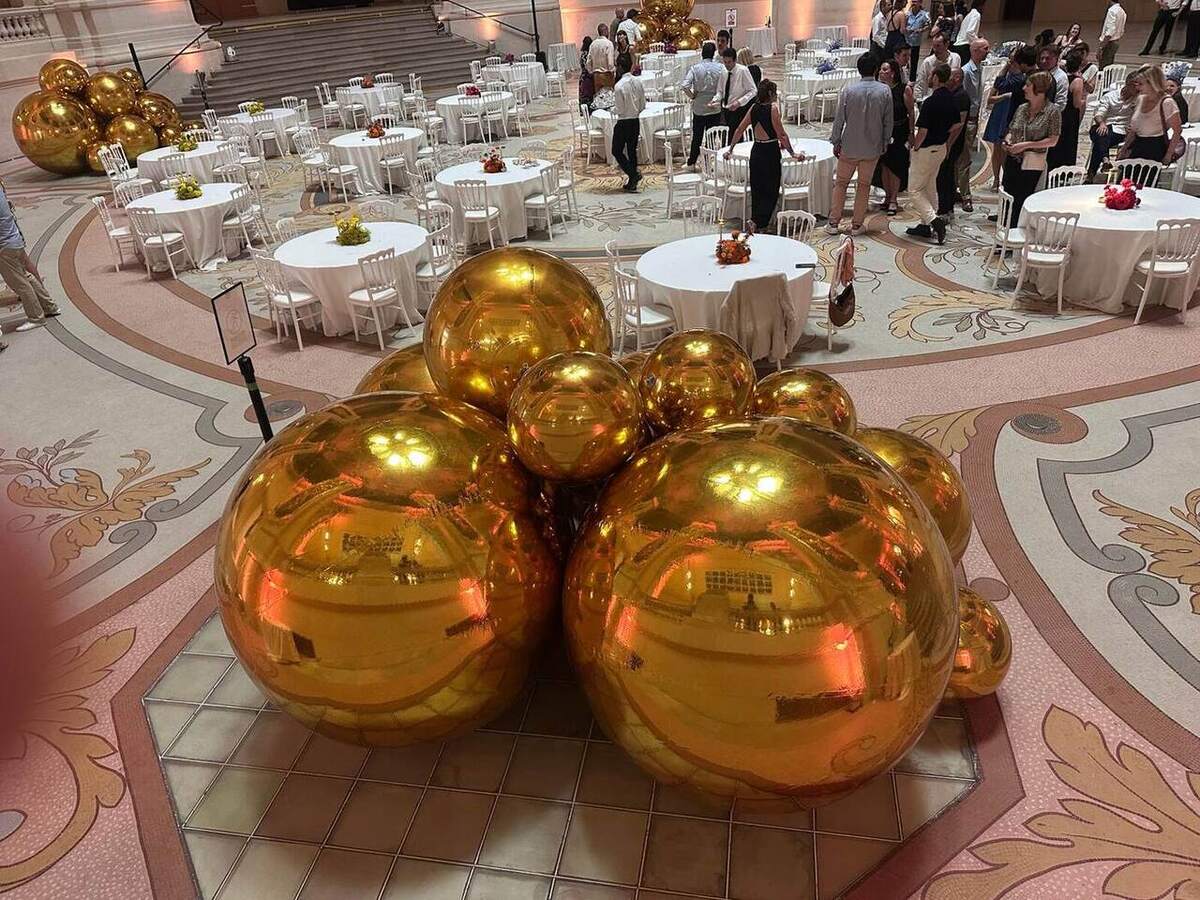 Composition de ballons miroirs dorés au premier plan d’un événement