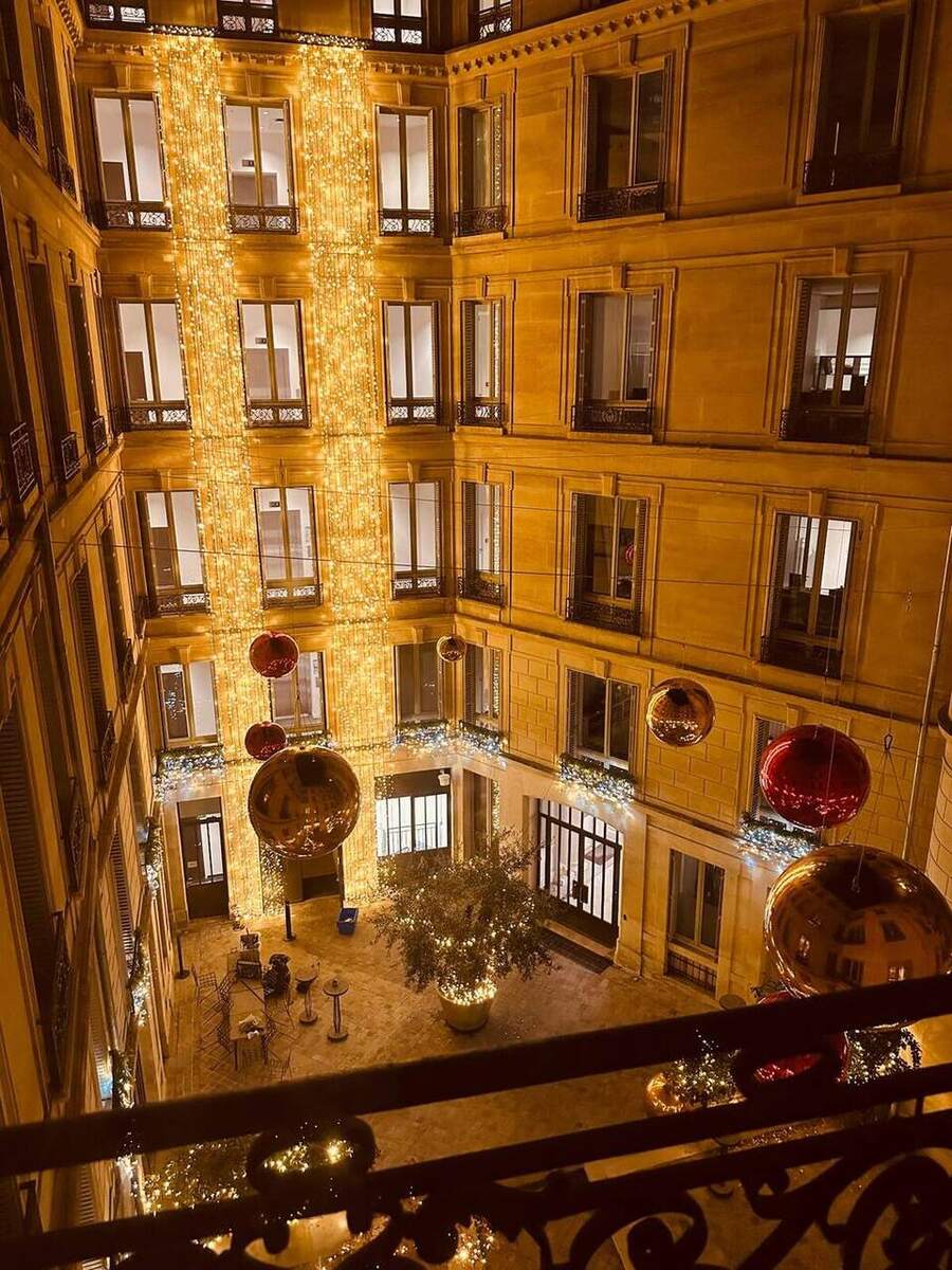 Ballons miroirs rouges et dorés suspendus dans une cour intérieure
