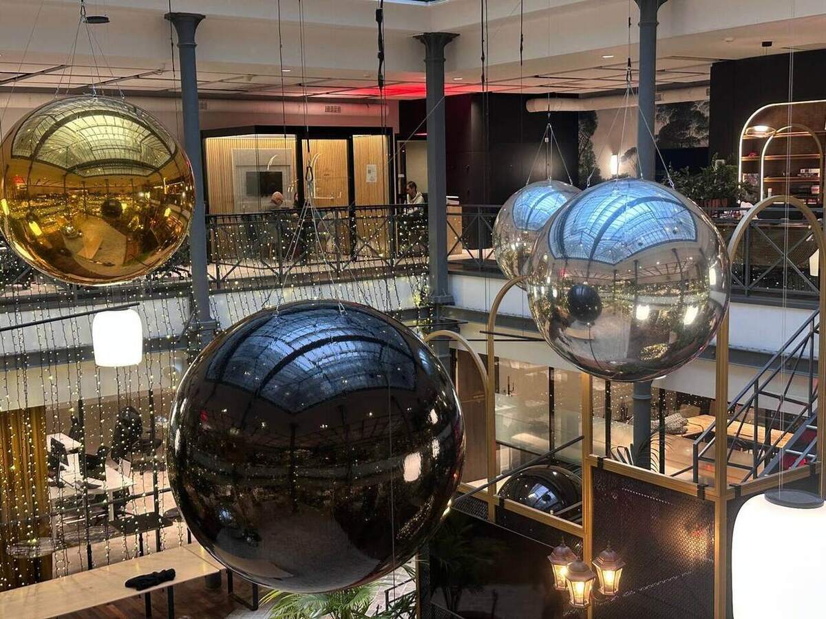 Composition monumentale de ballons miroirs suspendus dans un atrium
