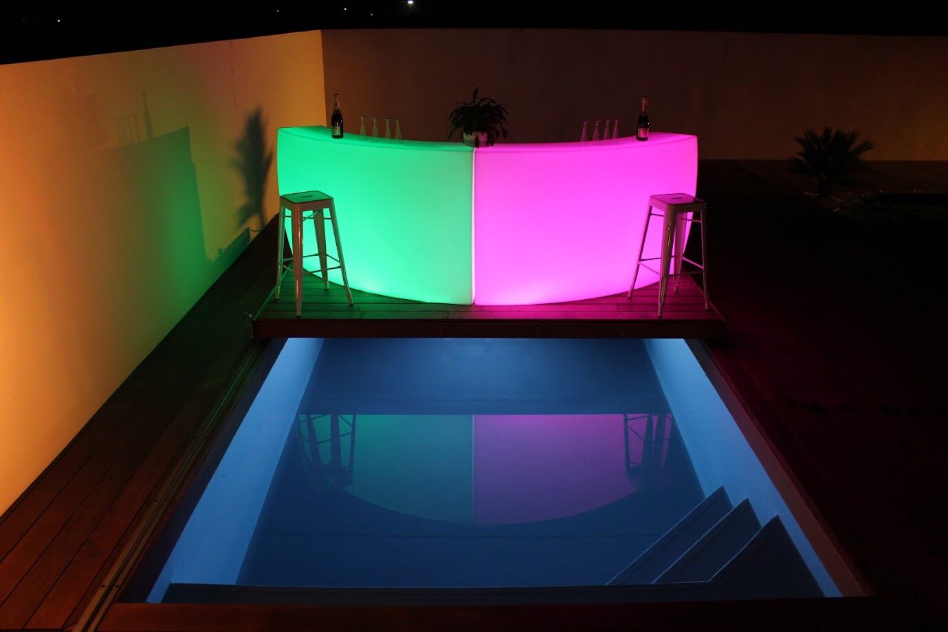 Mobilier lumineux vert et rose autour d’une piscine