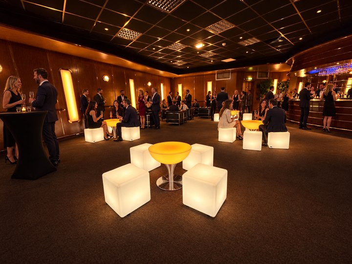 Table basse Lounge ambrée entourée de cubes blancs pendant une soirée cocktail