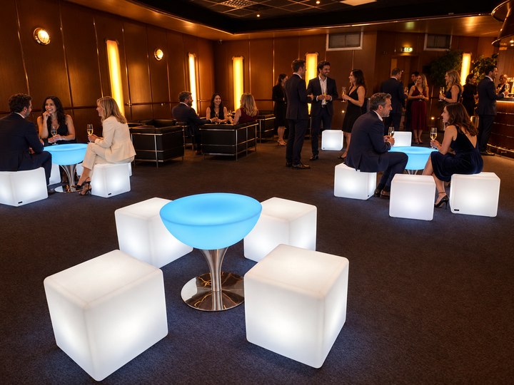 Table Lounge bleu glacé avec quatre cubes blancs et invités en arrière-plan