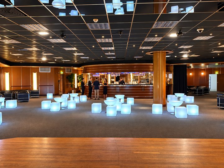 Tables Lounge blanc froid et cubes lumineux devant un bar avec des invités