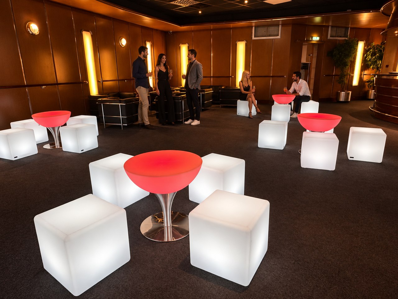 Table basse Lounge rouge au premier plan, invités dans le fond du salon