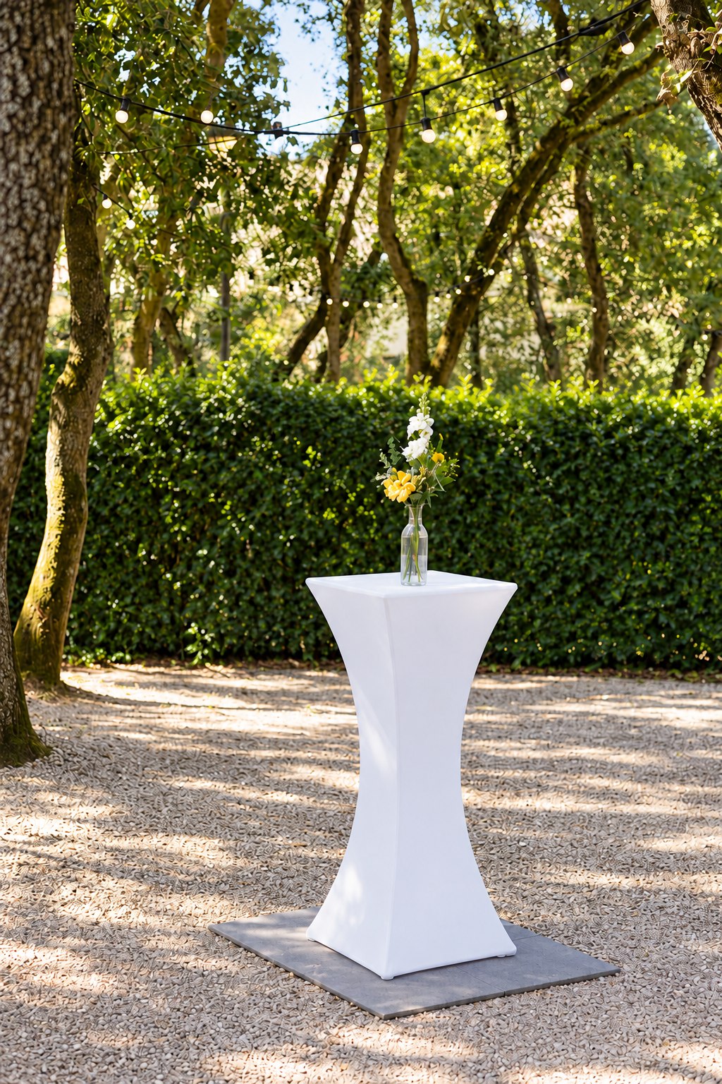 Mange-debout blanc cintré avec vase fleuri dans un jardin