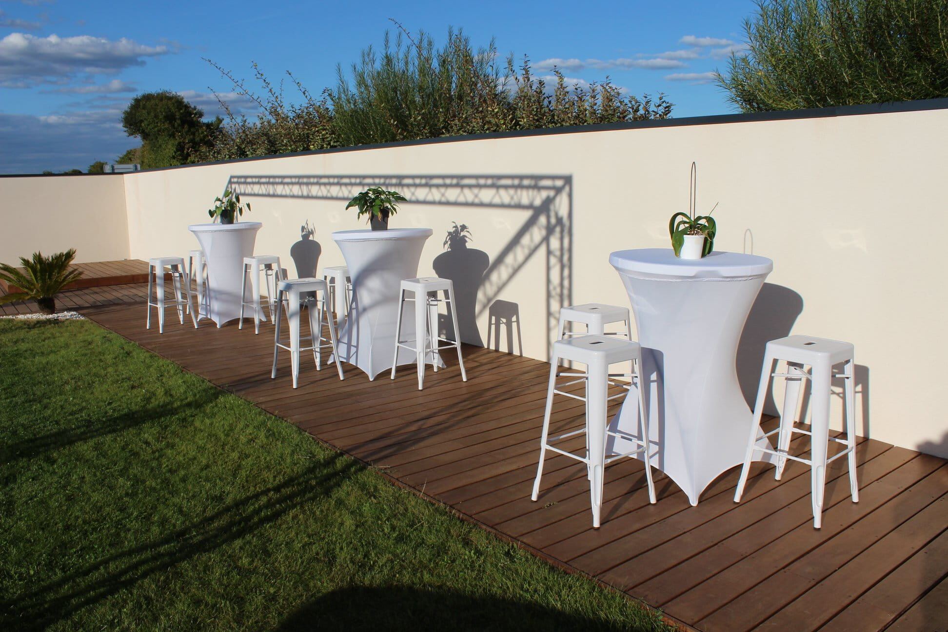 Tabourets hauts acier blancs et mange-debout installés dans un jardin