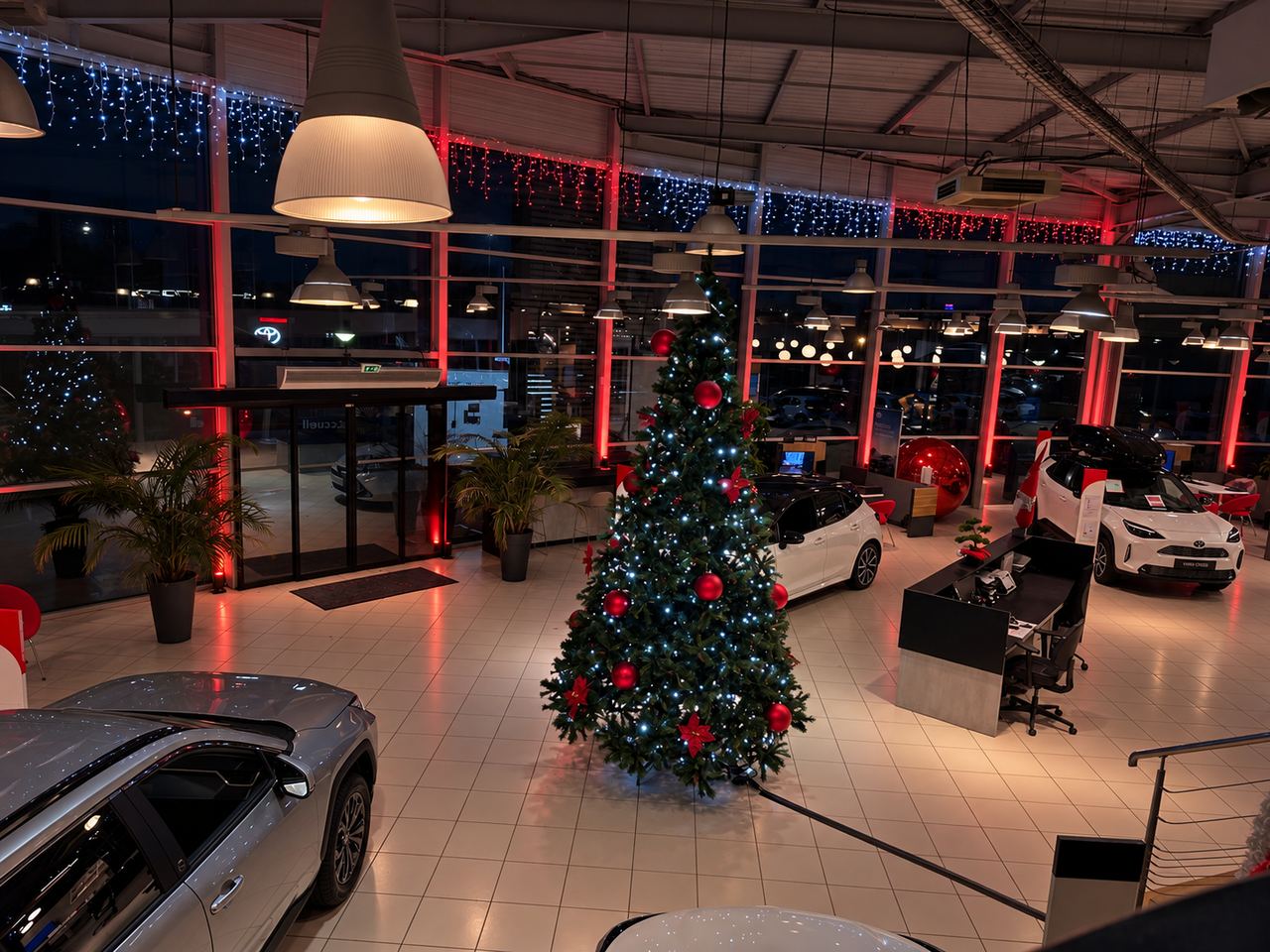 Sapin décoré devant les vitrines éclairées en rouge dans un showroom