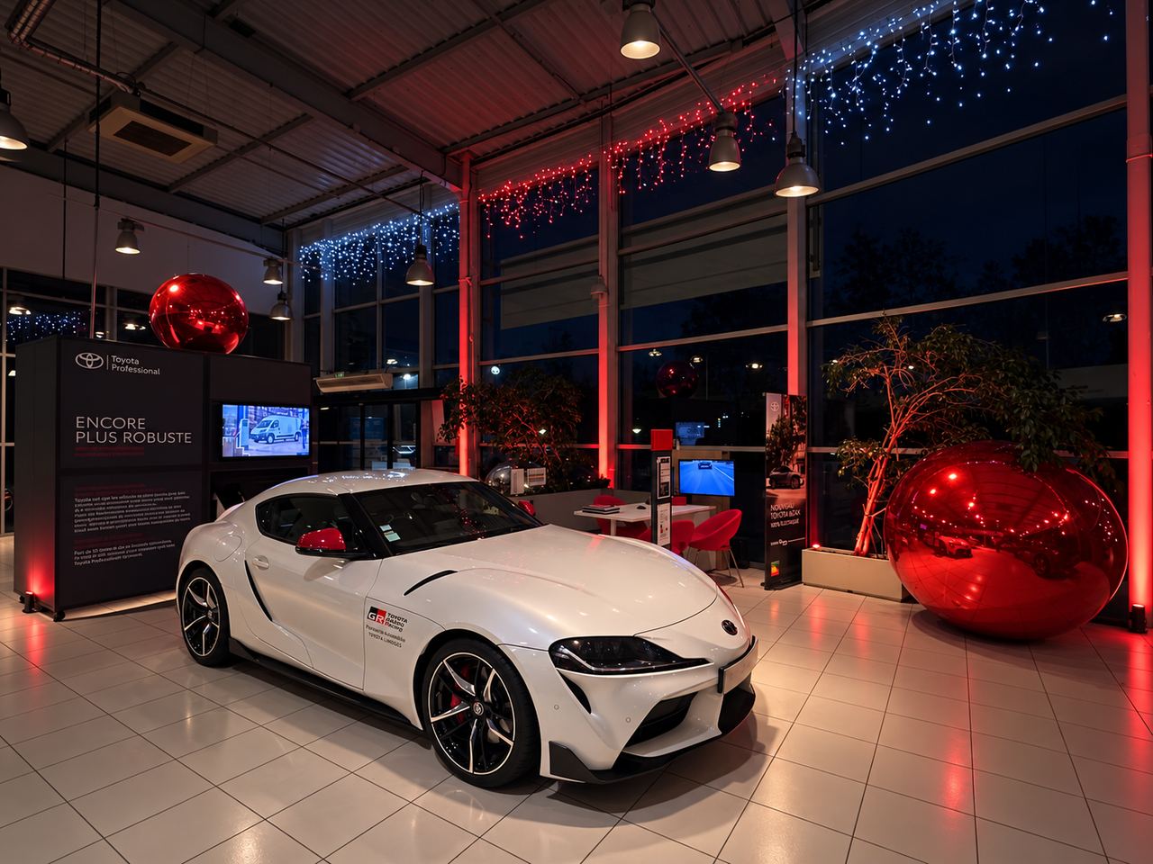 Voiture dans un showroom décoré de ballons rouges et de guirlandes de Noël