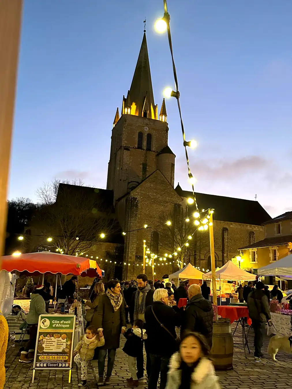 Marché de Noël avec guirlandes lumineuses devant une église