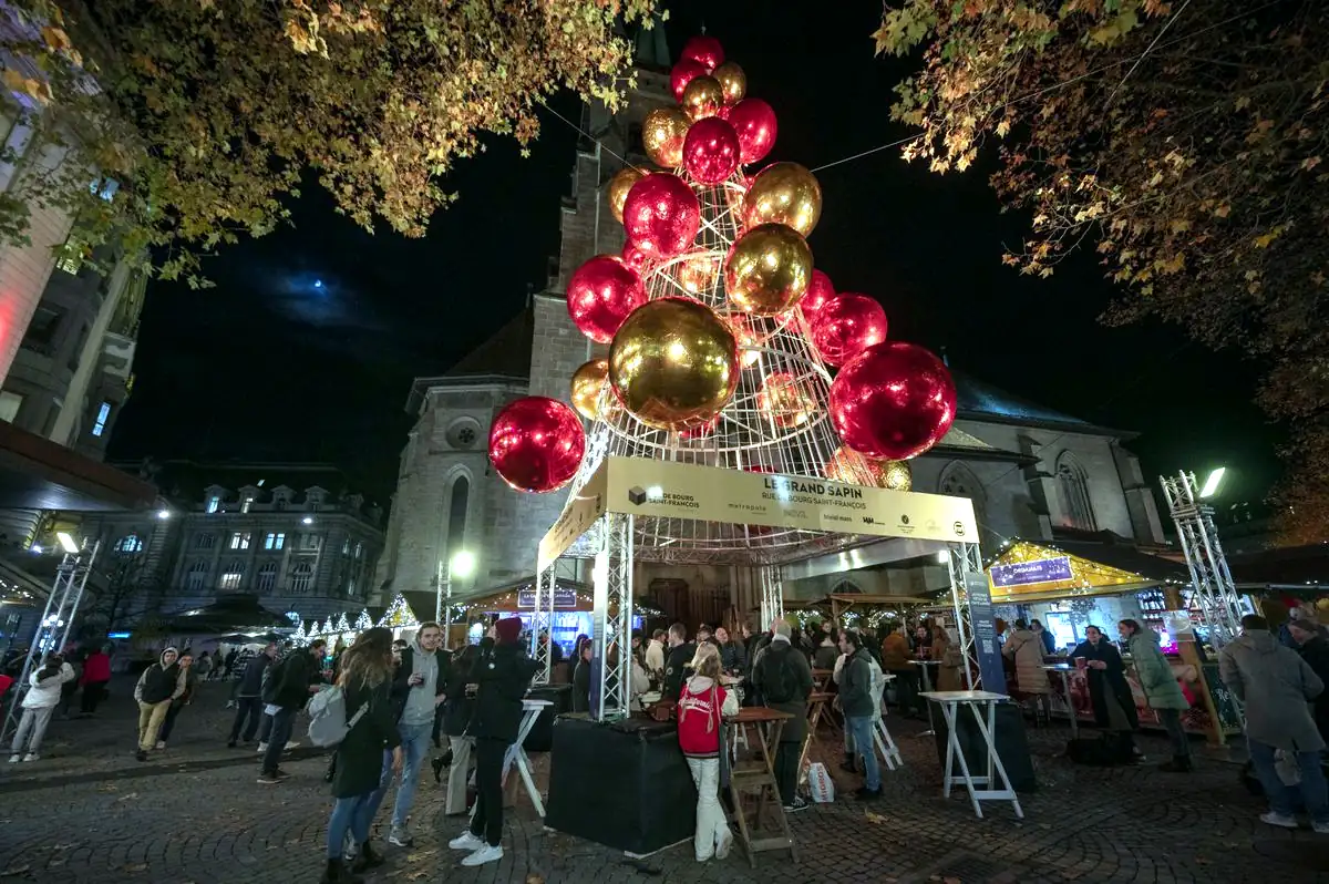 Grand sapin de Noël rouge et doré sur une place